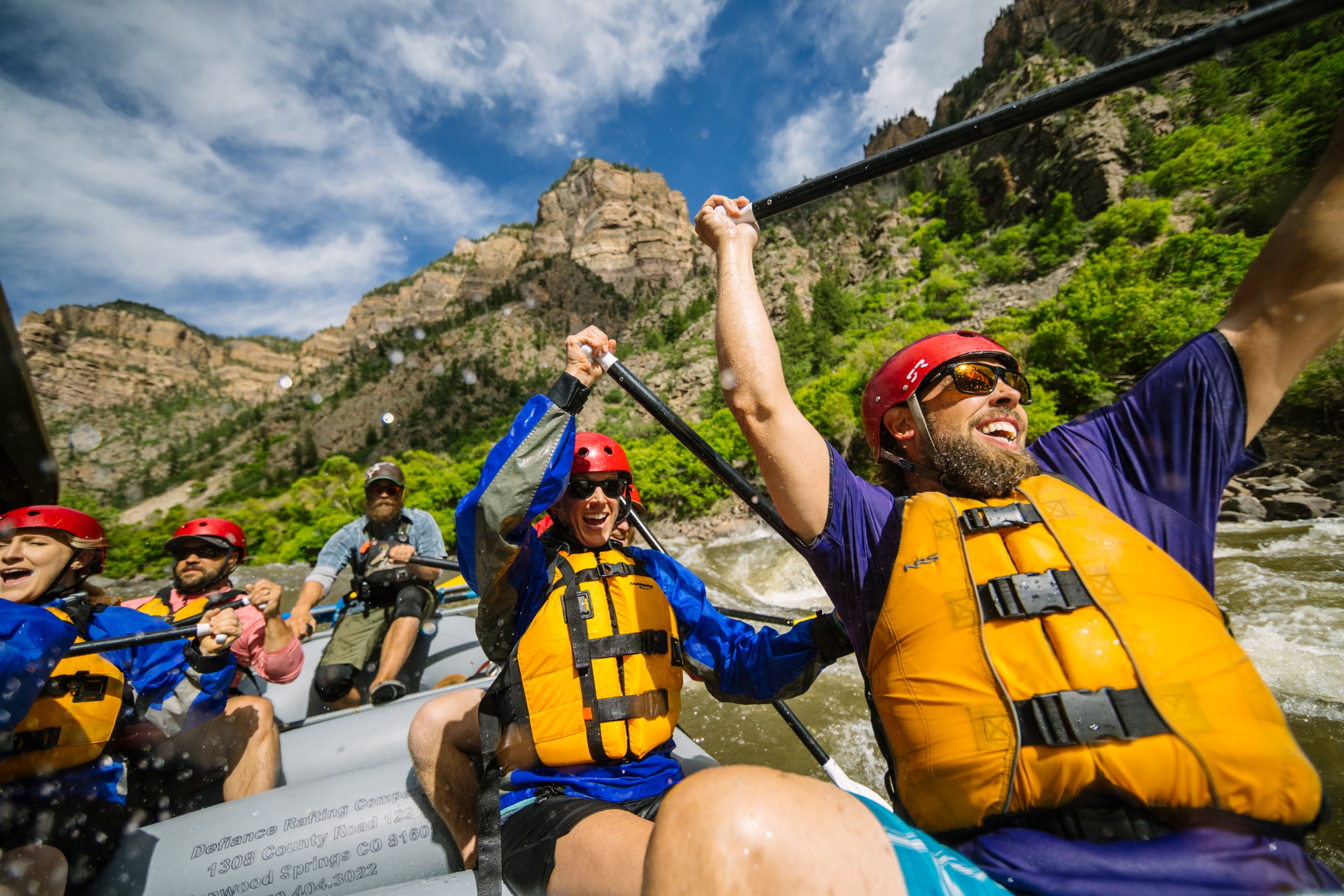 a colorado whitewater rafting group celebrates after going over a rapid.