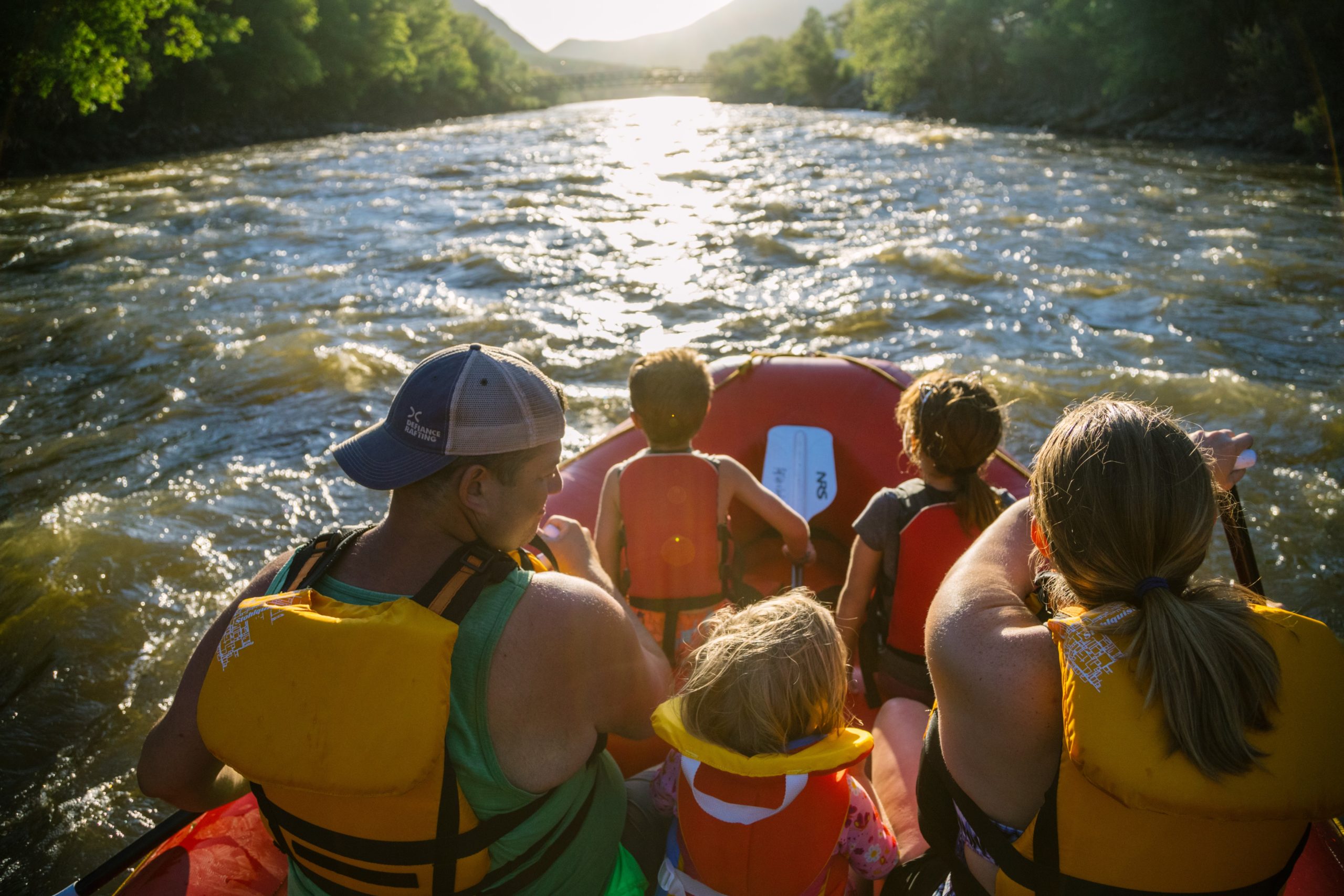 a family paddles down the river in a raft